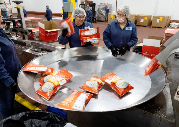Workers gather bags of Netflix cheddar-flavored popcorn at Eagle Foods manufacturing facility on March 11, 2024, in Waukegan. (Stacey Wescott/Chicago Tribune)