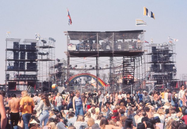 Fans look for a spot to sit at California Jam near the sound and light tower at the April 6, 1974 festival in Ontario. The stage with its signature rainbow arch design is in the background. (Courtesy Allen Pamplin)
