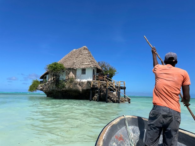 During high tide in fall 2021, a canoe carries Brooke and Chris Staggs to the famous The Rock restaurant, which sits in the Indian Ocean, off the eastern shores of Zanzibar. (Photo by Brooke Staggs, Orange County Register/SCNG)