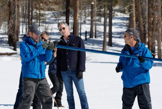 California Department of Water Resources Snow Surveys and Water Supply Forecasting Unit Water Engineers Andy Reising, right, and Anthony Burdock conduct the fourth media snow survey of the 2024 season at Phillips Station in the Sierra Nevada. Gov. Gavin Newsom, center, and California Natural Resources Agency Secretary Wade Crowfoot watch the process. The survey is held approximately 90 miles east of Sacramento off Highway 50 in El Dorado County. Photo taken April 2, 2024. (Fred Greaves / California Department of Water Resources)